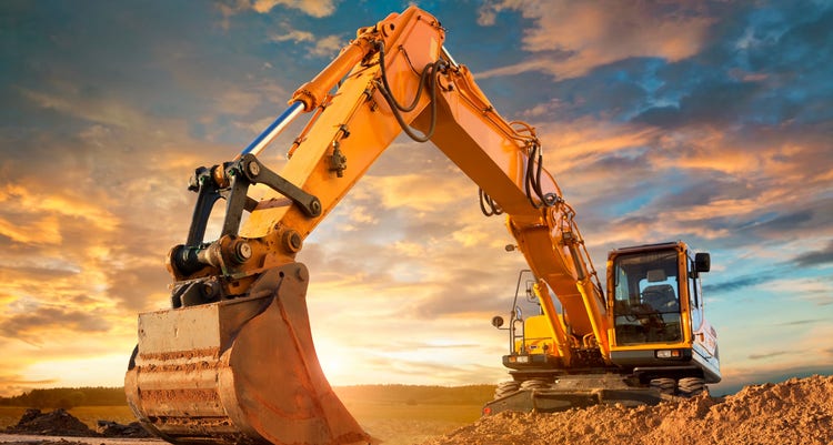 Construction equipment with sun setting behind it